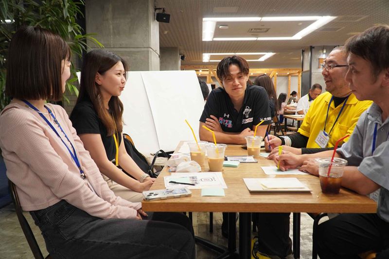 テーブルを囲んで選手と参加者が意見を出し合う様子