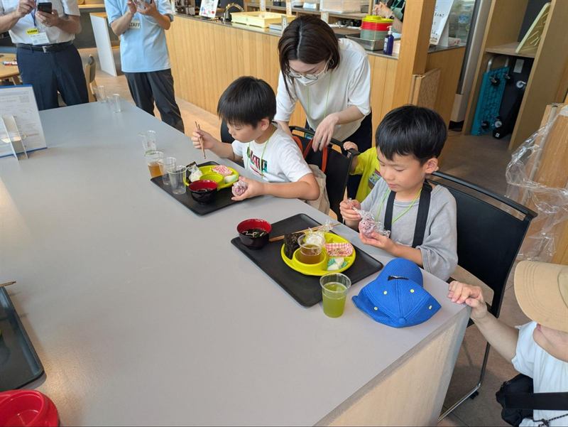 テーブルで食事をするこどもたちと付き添いの大人